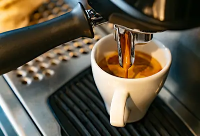 Cup of coffee being poured from a machine into a mug.